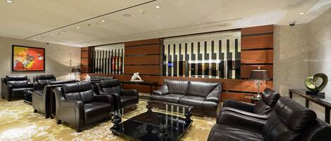 A modern living room with leather sofas, a glass coffee table, and a patterned carpet.
