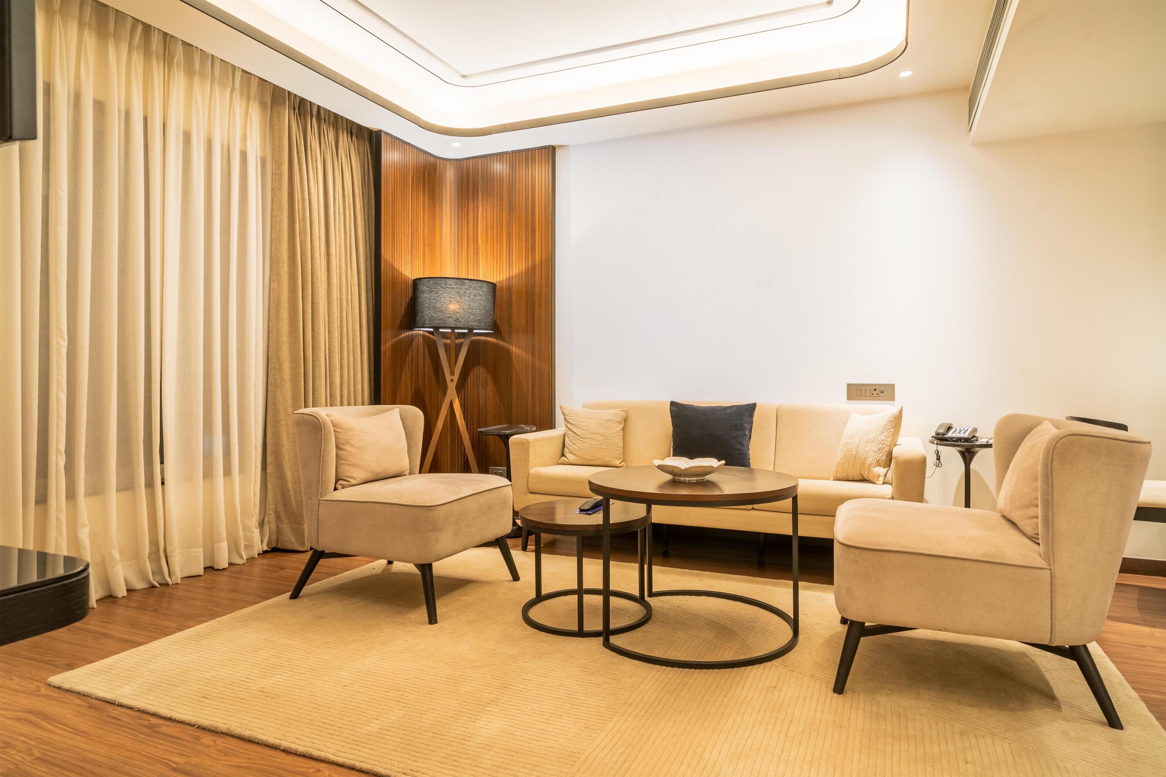 A modern living room with a sofa, two armchairs, a coffee table, a lamp, and a rug.