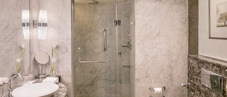 Un baño moderno con lavamanos de mármol, ducha con mampara de vidrio y un inodoro.