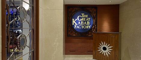 Un vestíbulo con un letrero que dice "The Great Kebab Factory" y un podio de madera decorativo.