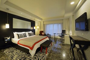 Une chambre d’hôtel moderne dotée d’un grand lit, d’un bureau, d’une télévision et d’un tapis à motifs zébrés.