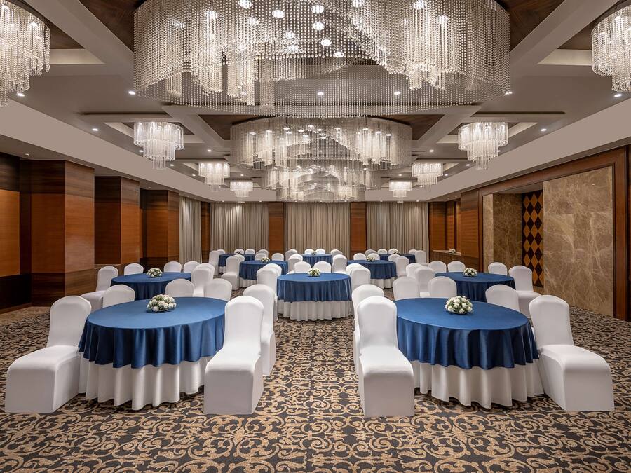 A conference room with round tables, white chairs, and blue tablecloths.