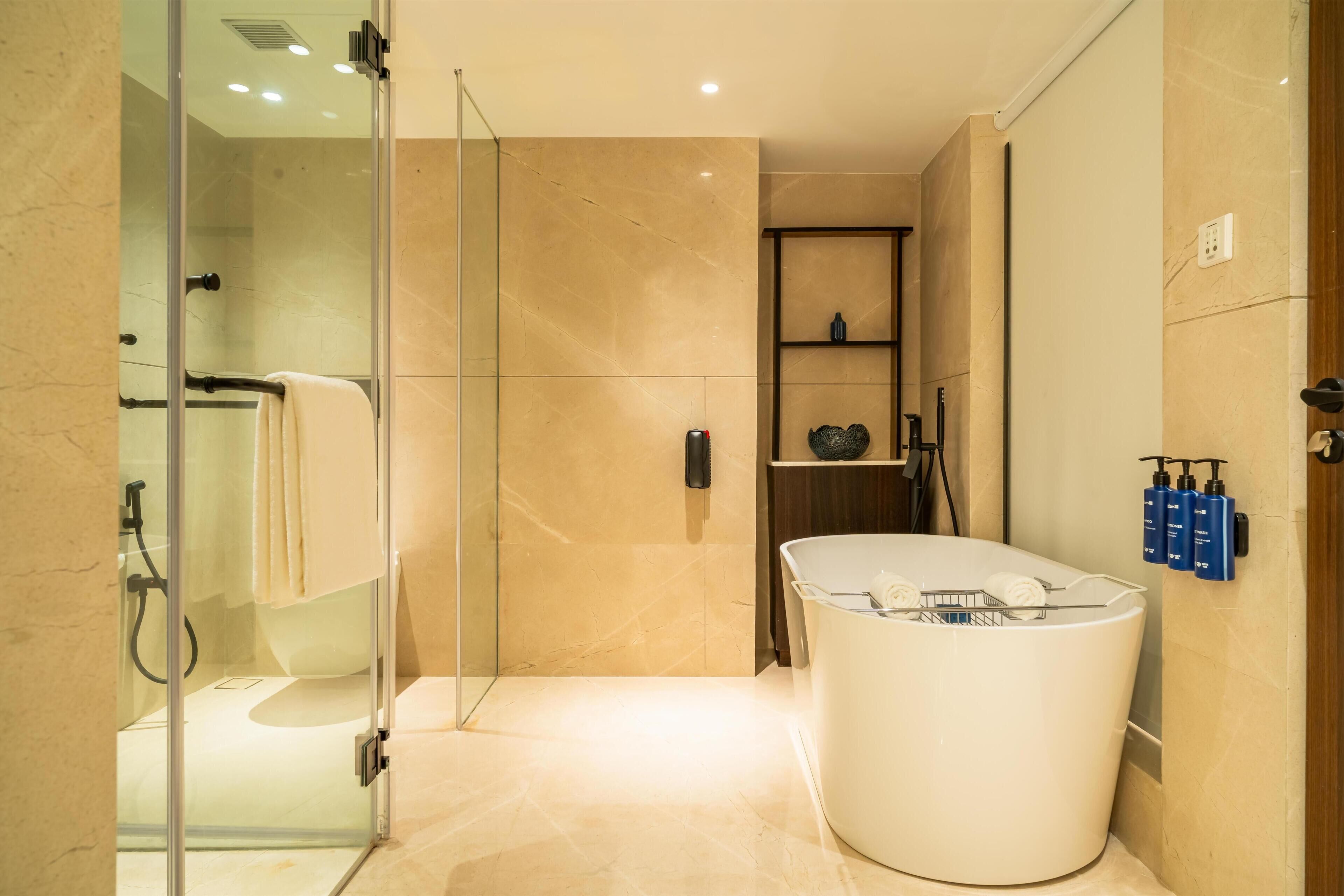 Une salle de bain moderne avec une douche à parois de verre, une baignoire sur pieds et une étagère contenant des articles de toilette.