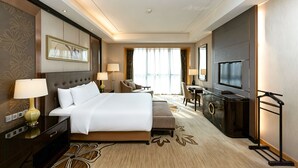 Habitación de hotel con una cama grande, un escritorio, un televisor y una zona de estar.