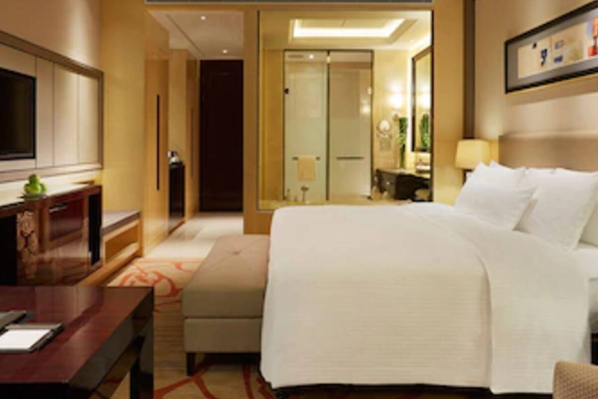Ein Hotelzimmer mit Bett, Schreibtisch, Fernseher und Spiegel.