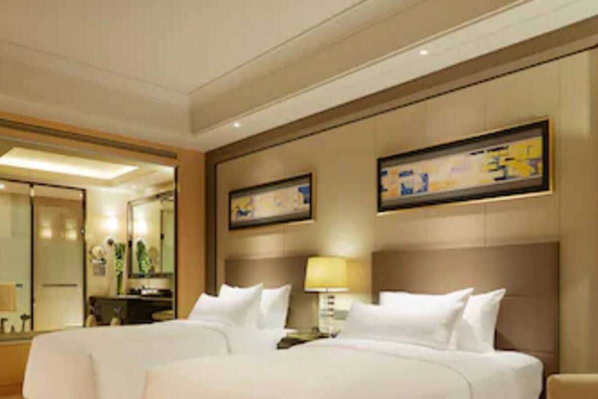 Ein Hotelzimmer mit zwei Betten, einem großen Spiegel, einem Gemälde und einem Teppichboden.