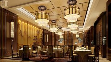 A dining area with multiple tables and chairs, ornate chandeliers, and traditional wall decor.