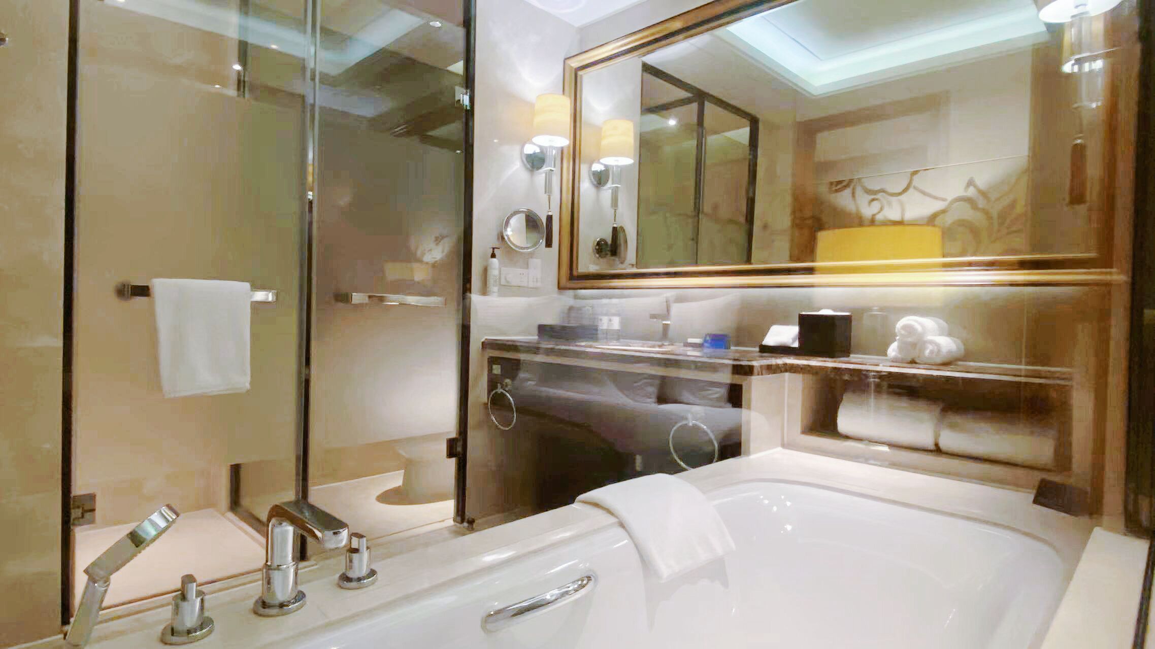 A modern bathroom with a glass-enclosed shower, a large bathtub, and a vanity with a mirror.