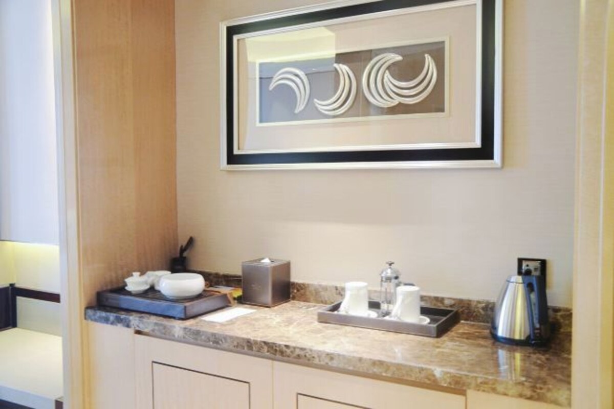 A modern bathroom with a marble countertop, a framed abstract artwork, and a coffee maker.