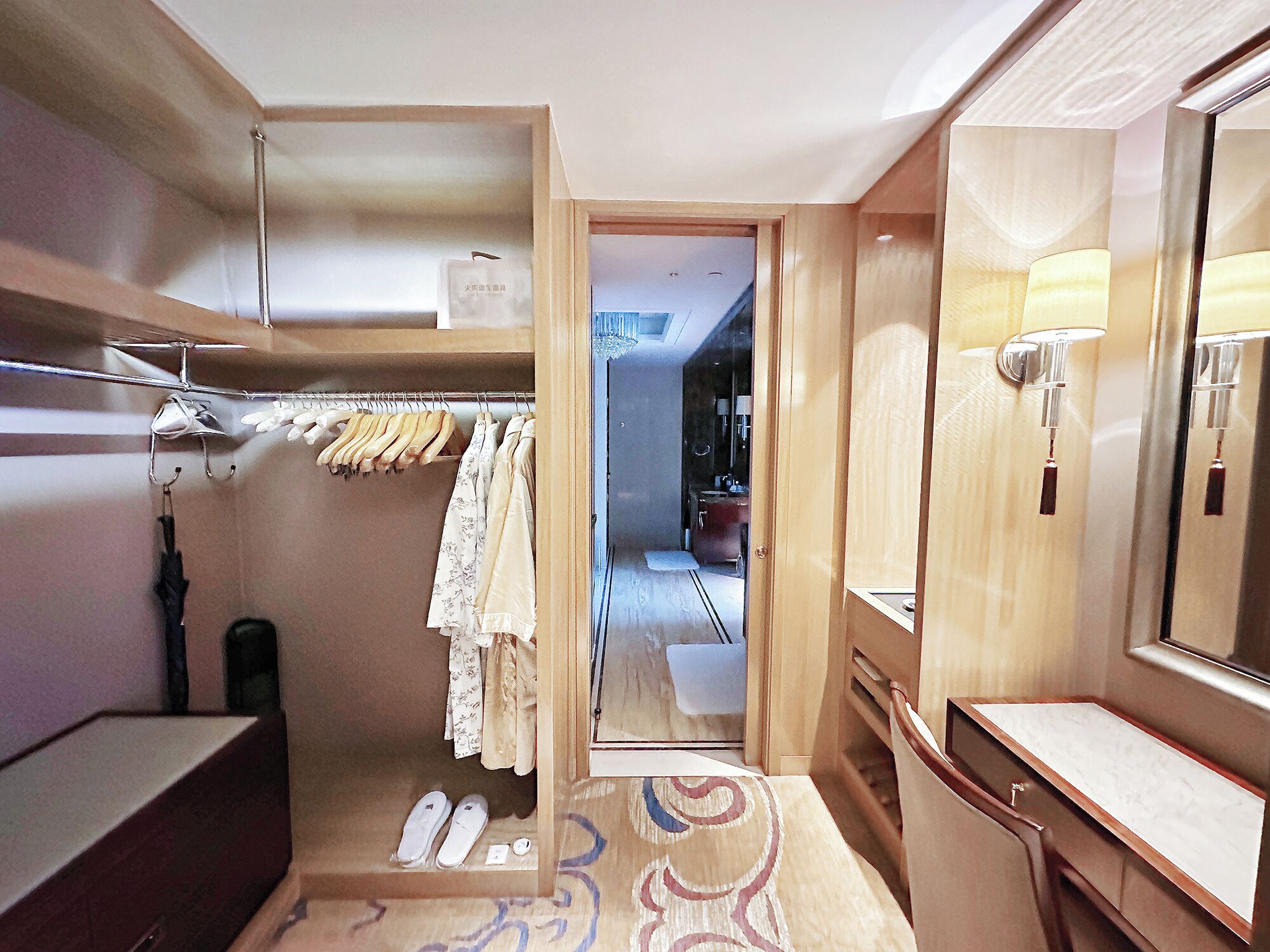 A hotel room with a walk-in closet, a mirror, and a bathroom with a shower.
