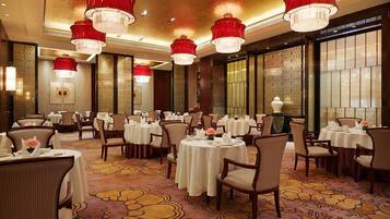 A restaurant with round tables, red chandeliers, and patterned carpet.