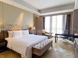 Una habitación de hotel con una cama grande, un escritorio, una silla y un sofá.
