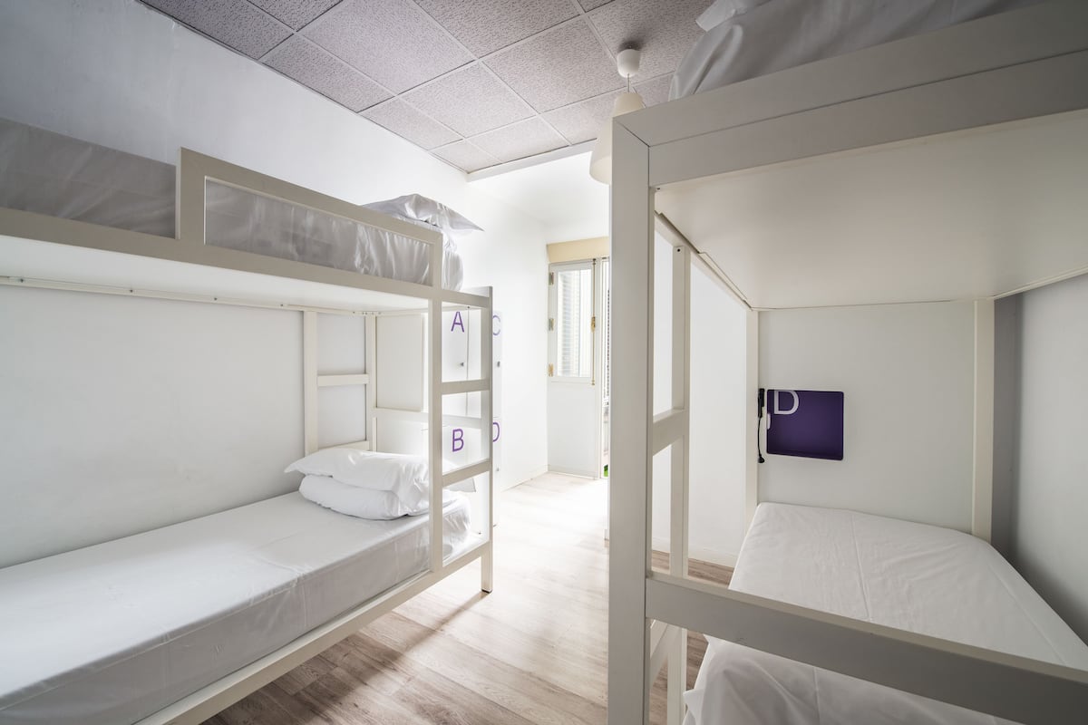 Une pièce avec des lits superposés, un plafond blanc et une porte qui donne sur une autre pièce.