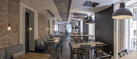 A modern cafe with exposed brick walls, wooden tables, and black pendant lighting.