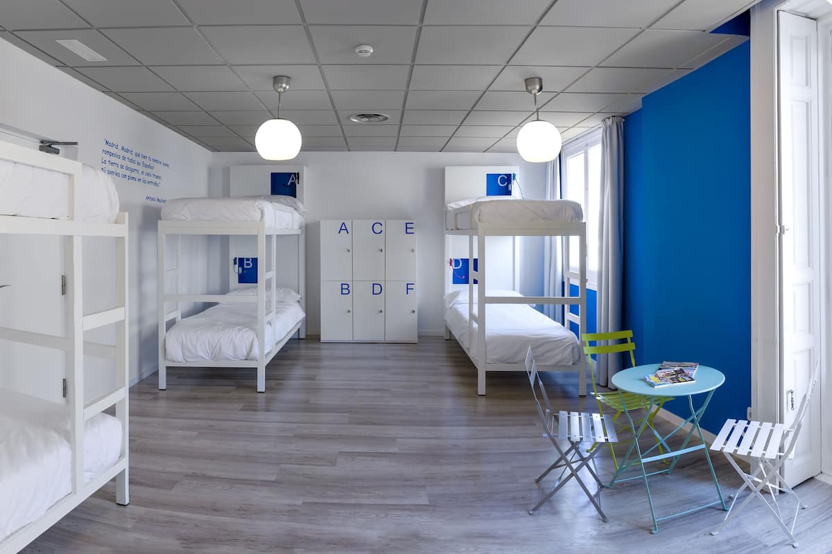 Une chambre avec des lits superposés, un bureau et une chaise. Il y a des armoires avec des lettres sur le mur.
