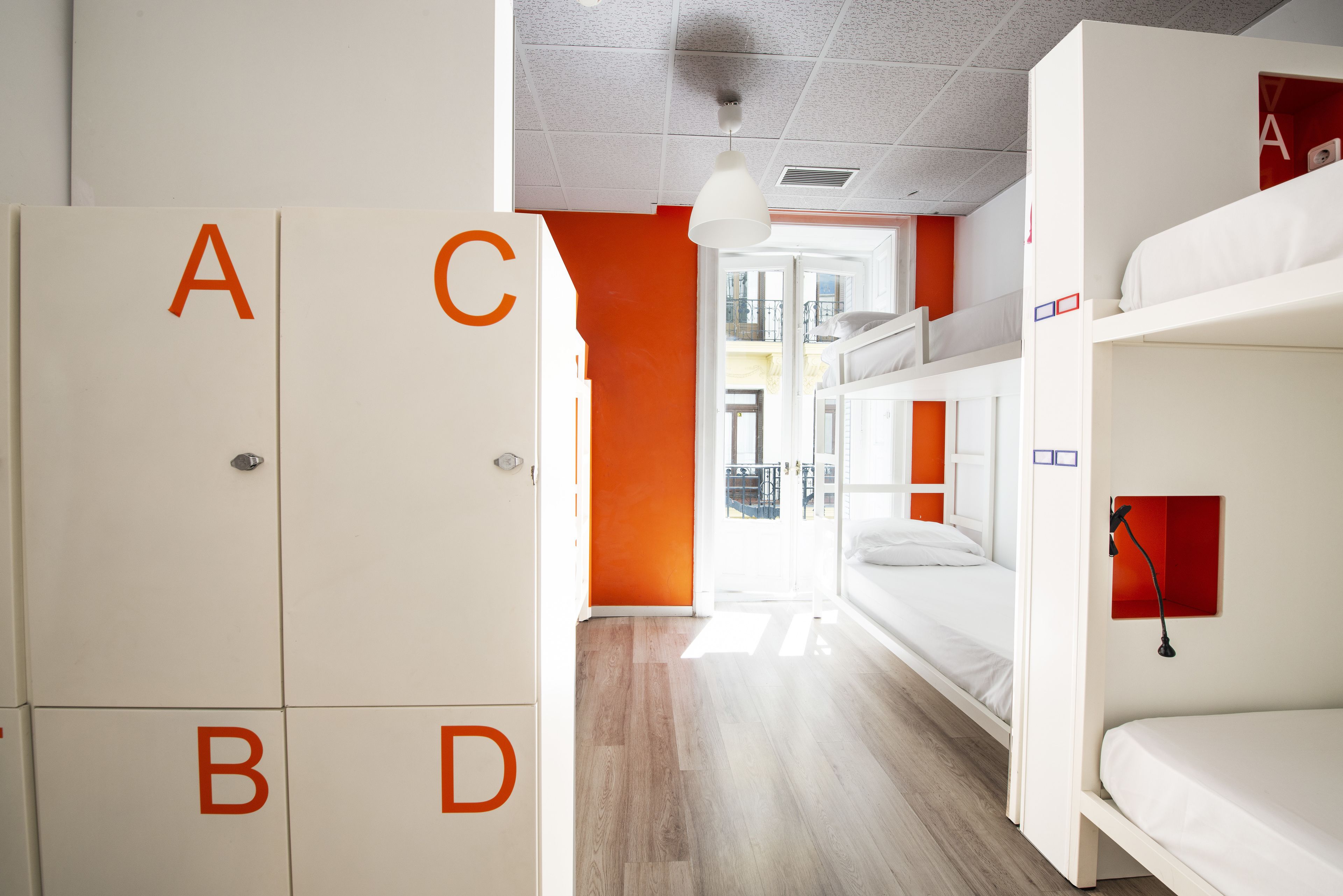 Et sovesalværelse med køjesenge, en garderobe med bogstaver på etiket og en orange væg.