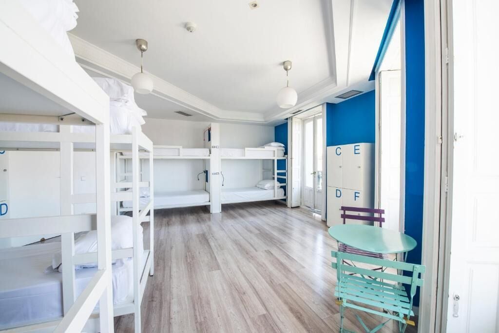 A room with bunk beds, a small table, and a chair. There are cabinets with letters on them.
