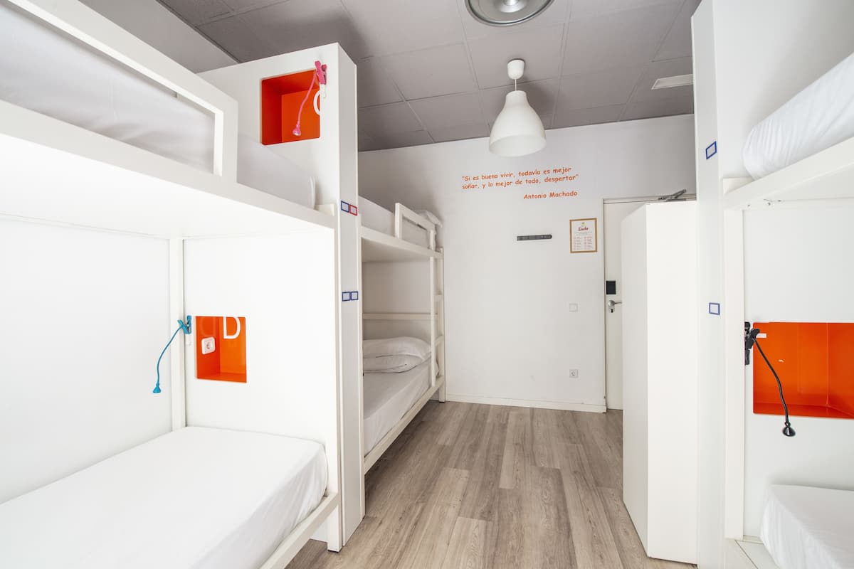 Une chambre de dortoir avec des lits superposés, un plafond blanc et un mur orné d’une citation inspirante.