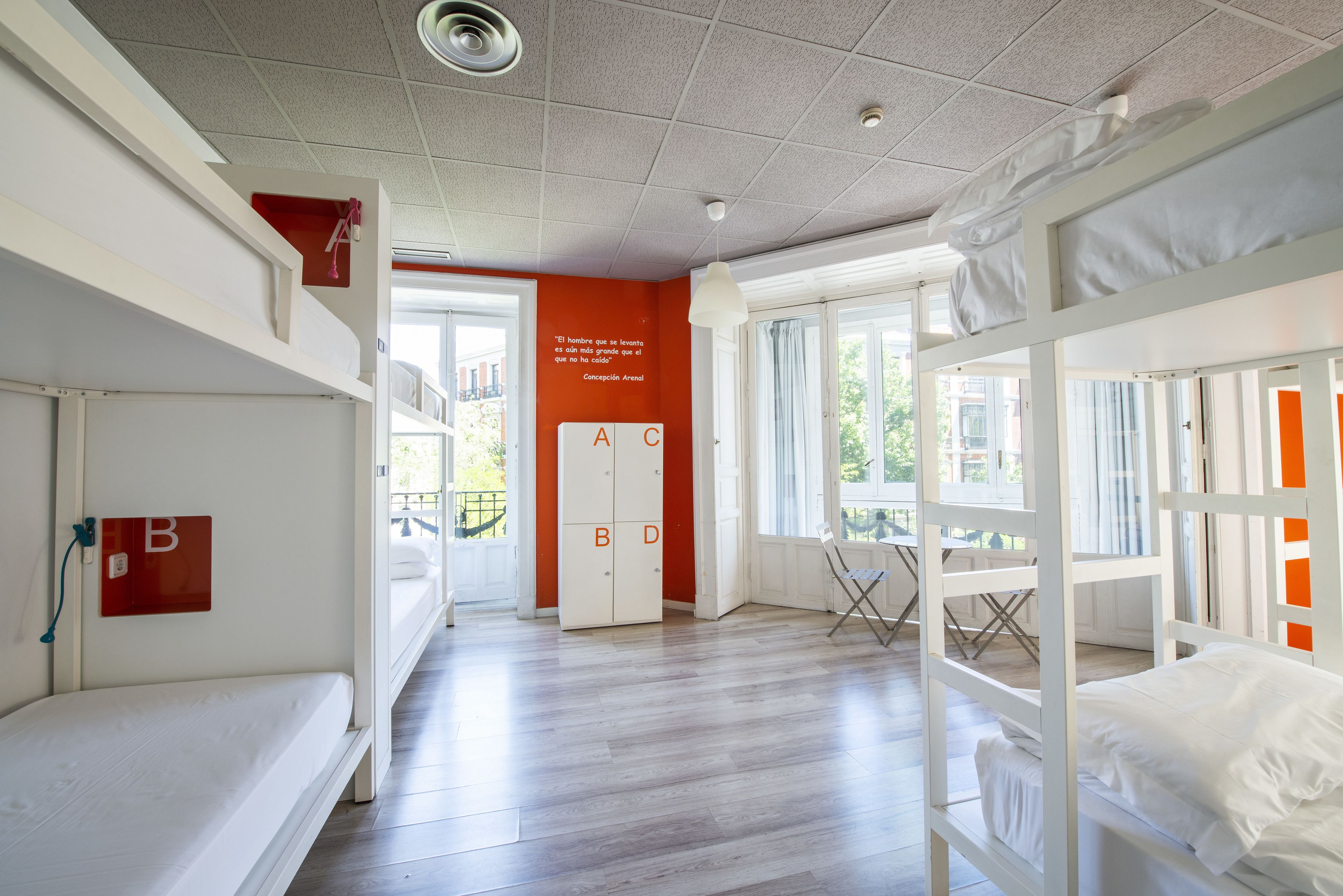 A dormitory room with bunk beds, a desk, and a window.