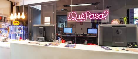 Et moderne kontor med flere HP kontorarbejdsstationer, et neonskilt med teksten ”¿Qué Paso?” og forskelligt kontorinventar på skrivebordene.
