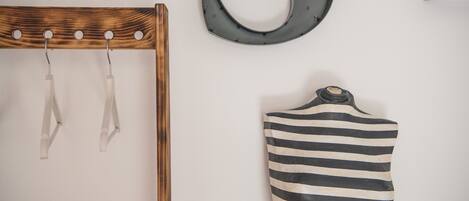 Una silla de madera con un gancho de metal y un objeto a rayas blanco y negro en la pared.