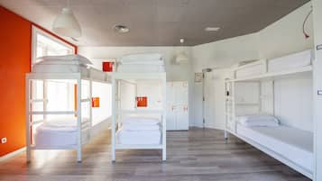Un dormitorio con literas, una ventana y una puerta con señales de salida de emergencia.
