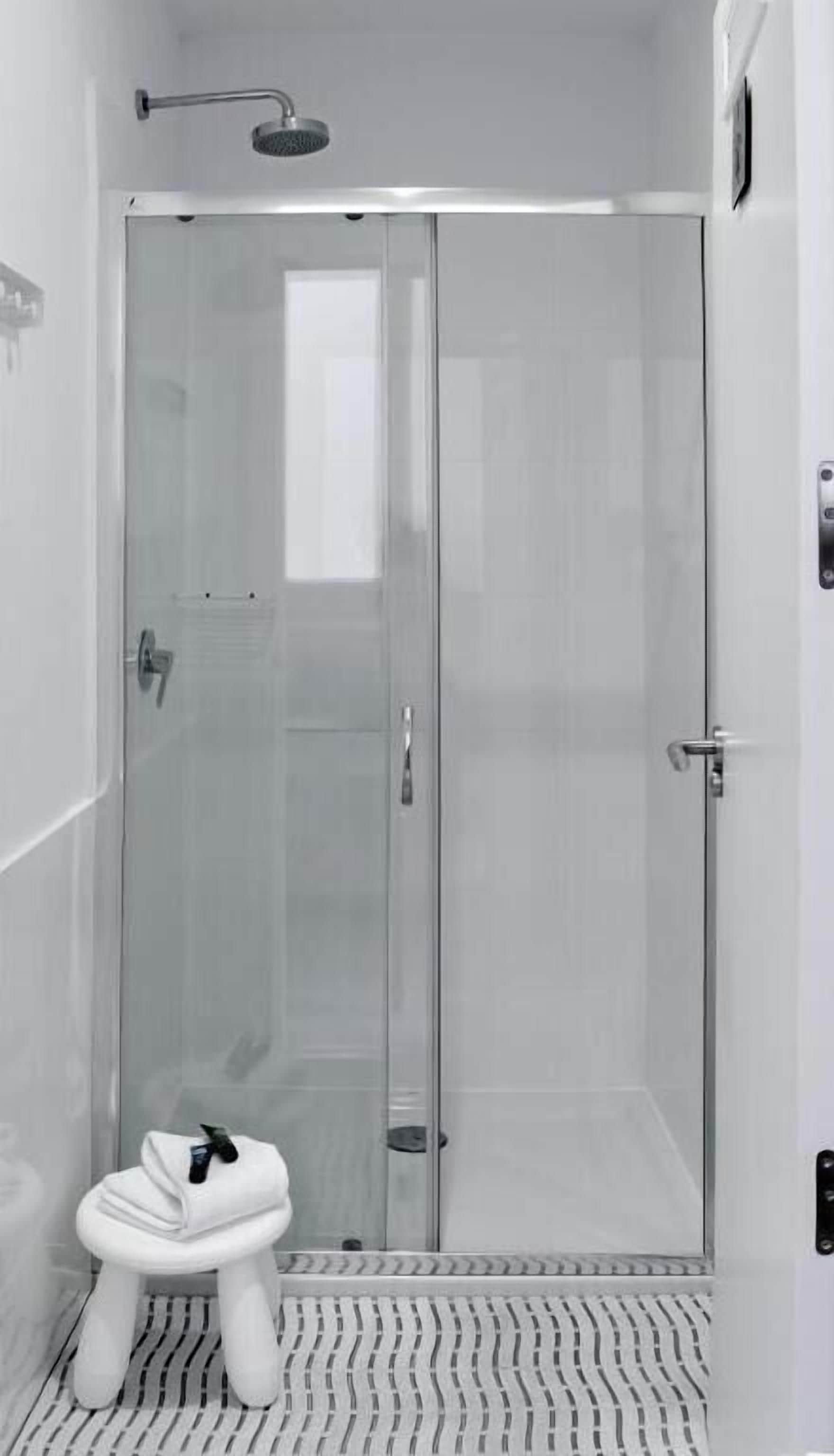 A modern bathroom with a glass shower enclosure, a white toilet, and a striped floor.