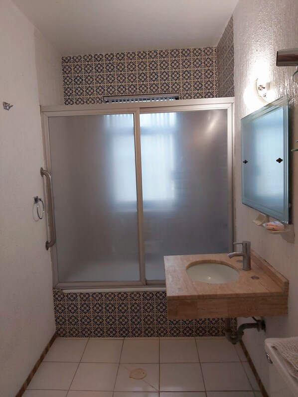 Un bagno con box doccia, lavabo con specchio e piastrelle decorate sulle pareti.