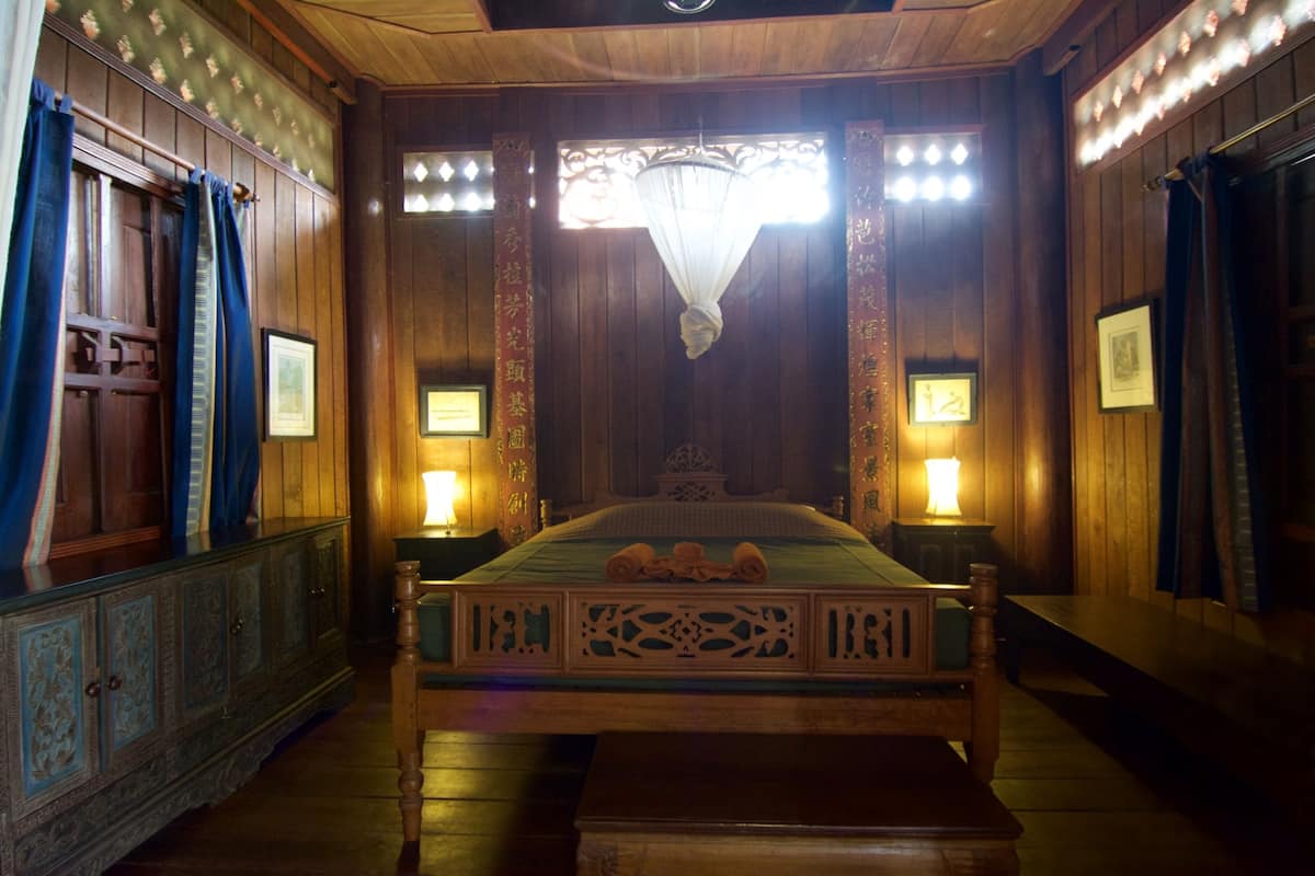 Une chambre traditionnelle avec un lit en bois, deux lampes de chevet et un lustre.