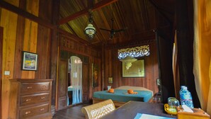 A wooden room with a bed, a desk, a dresser, and a ceiling fan. - Rajabori Villas (Kratie)