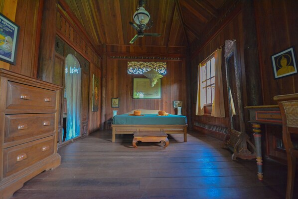 A wooden room with a bed, dresser, and a ceiling fan.