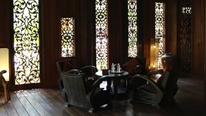 A dining area with a round table and chairs, wooden flooring, and decorative stained glass windows. - Rajabori Villas (Kratie)