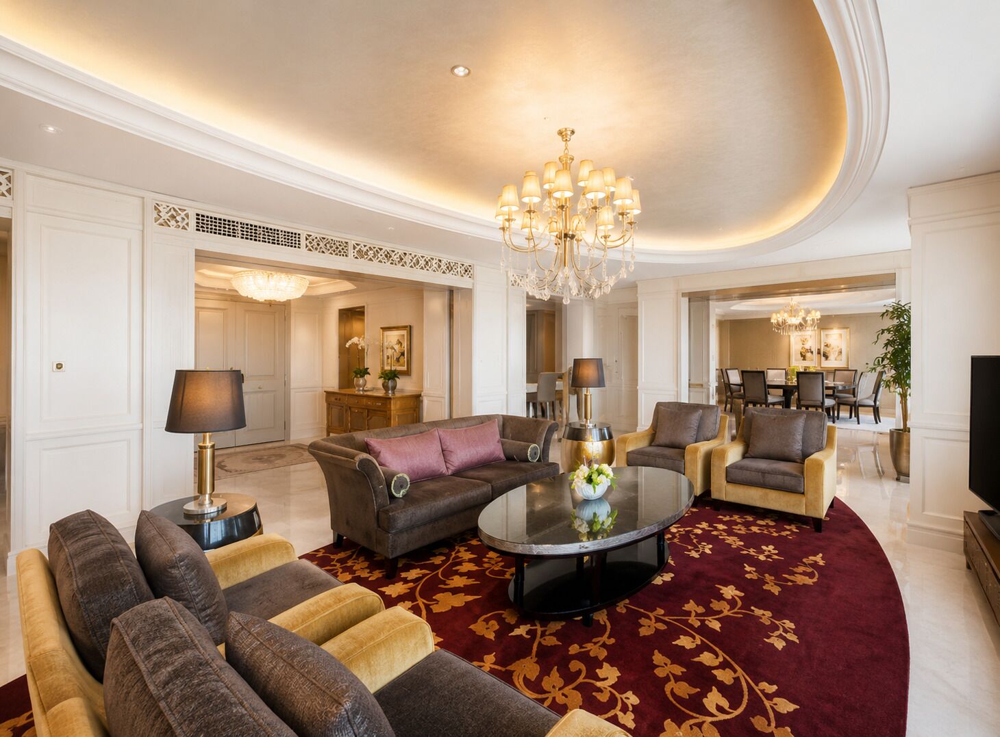 A spacious living room with a round coffee table, sofas, and a chandelier.