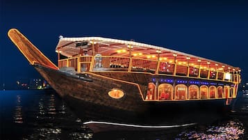 Un barco de madera tradicional con cubierta protegida y varias ventanas, iluminado por luces interiores.