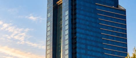 A high-rise building with the name 'Dusit Thani' on its facade, featuring a modern glass exterior and two antennae on top.