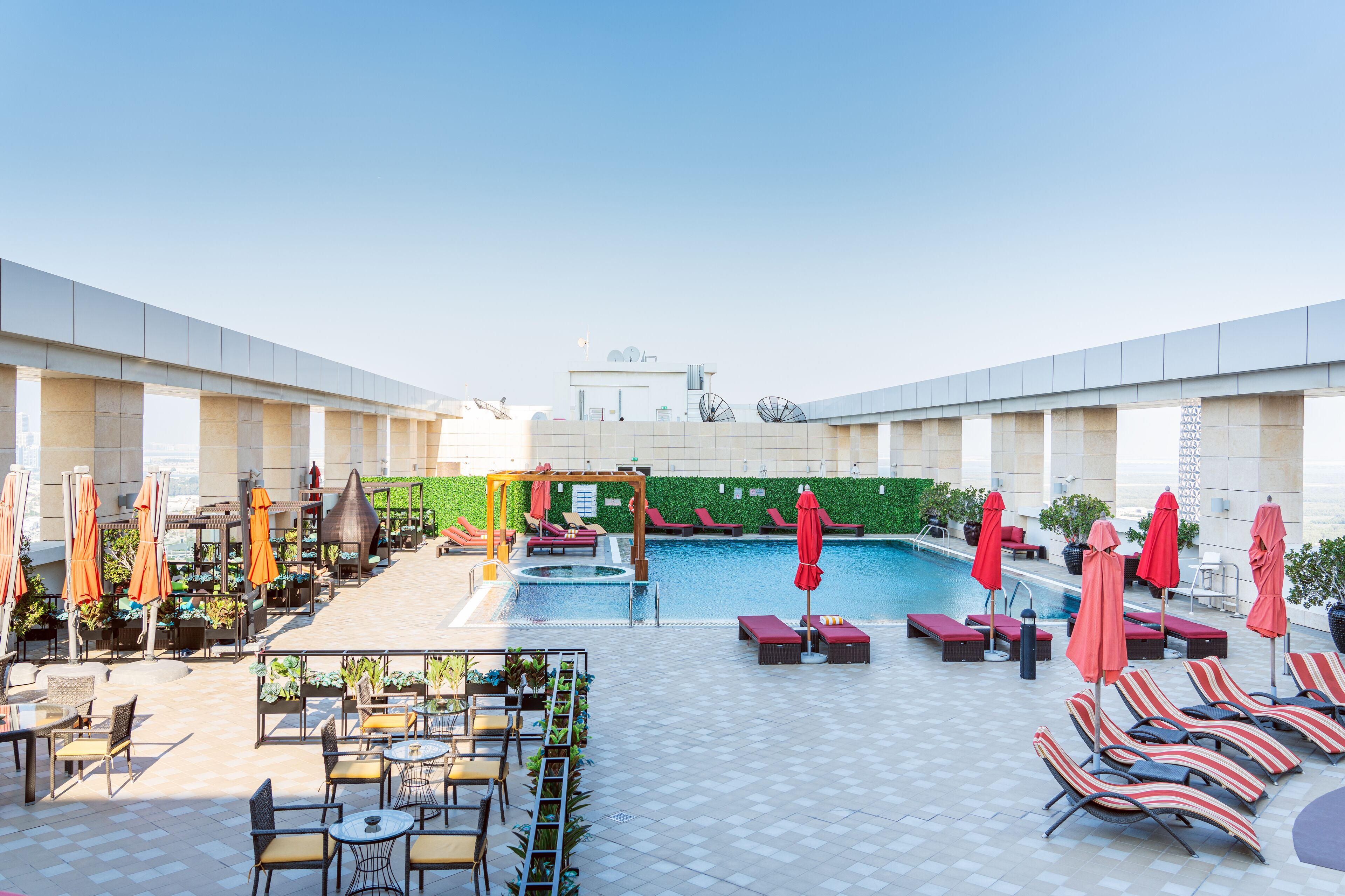 Un espace piscine aménagé sur le toit, avec des chaises longues, des parasols et une petite piscine.