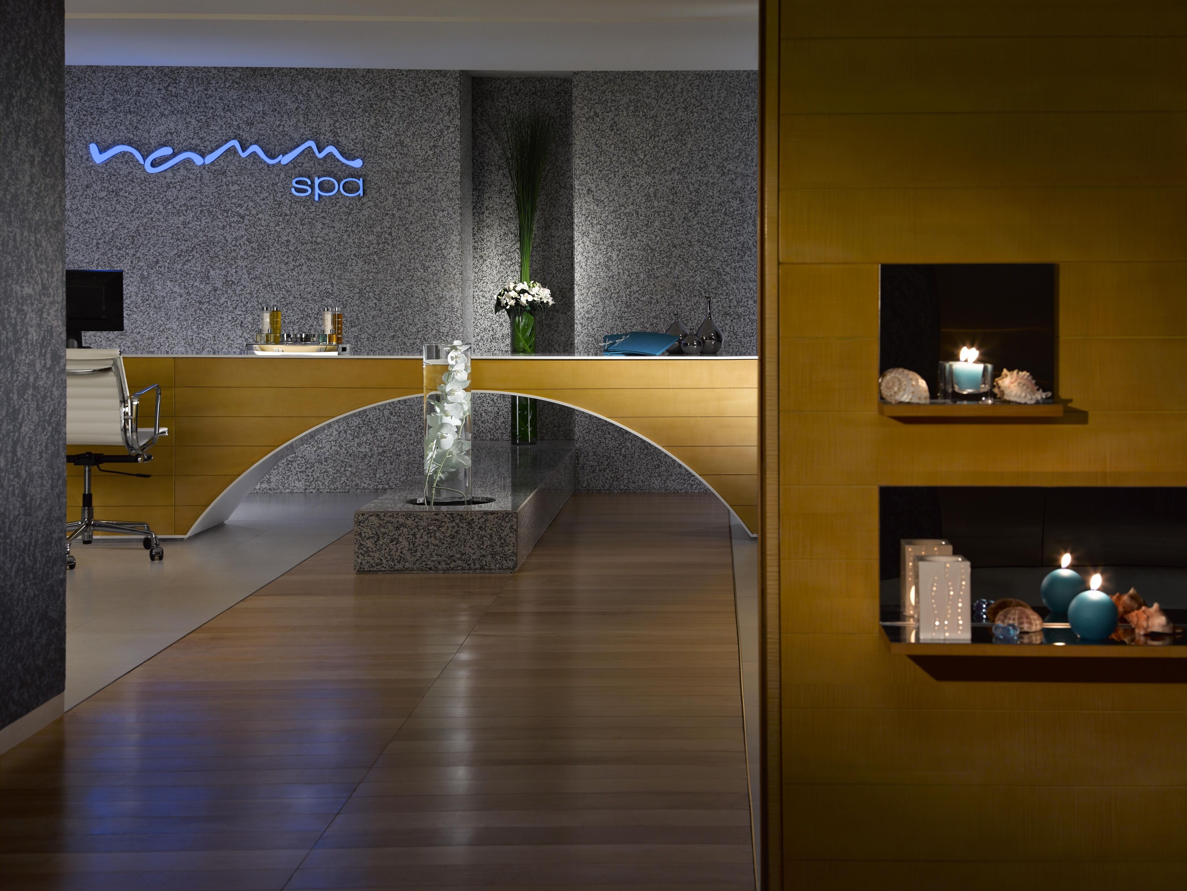 A reception area with a modern design, featuring a reception desk, a neon sign, and a decorative glass sculpture.