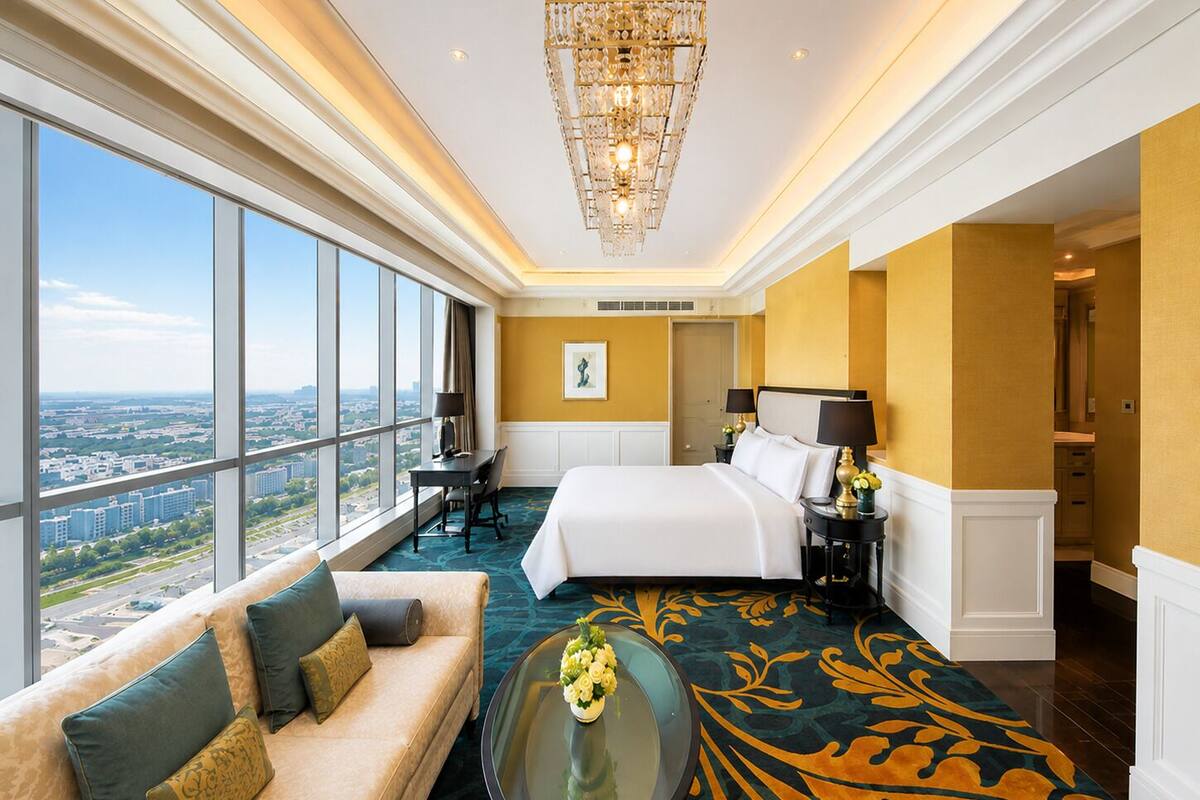 A hotel room with a large bed, a sofa, a desk, and a view of the city.