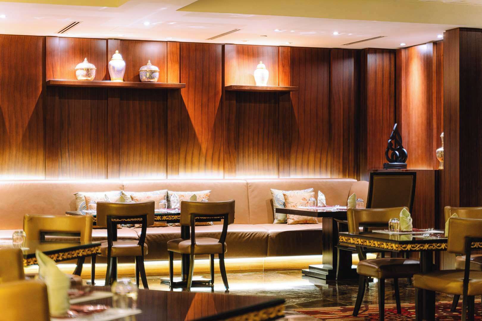 A restaurant with wooden paneling, cushioned seating, and tables set for dining.