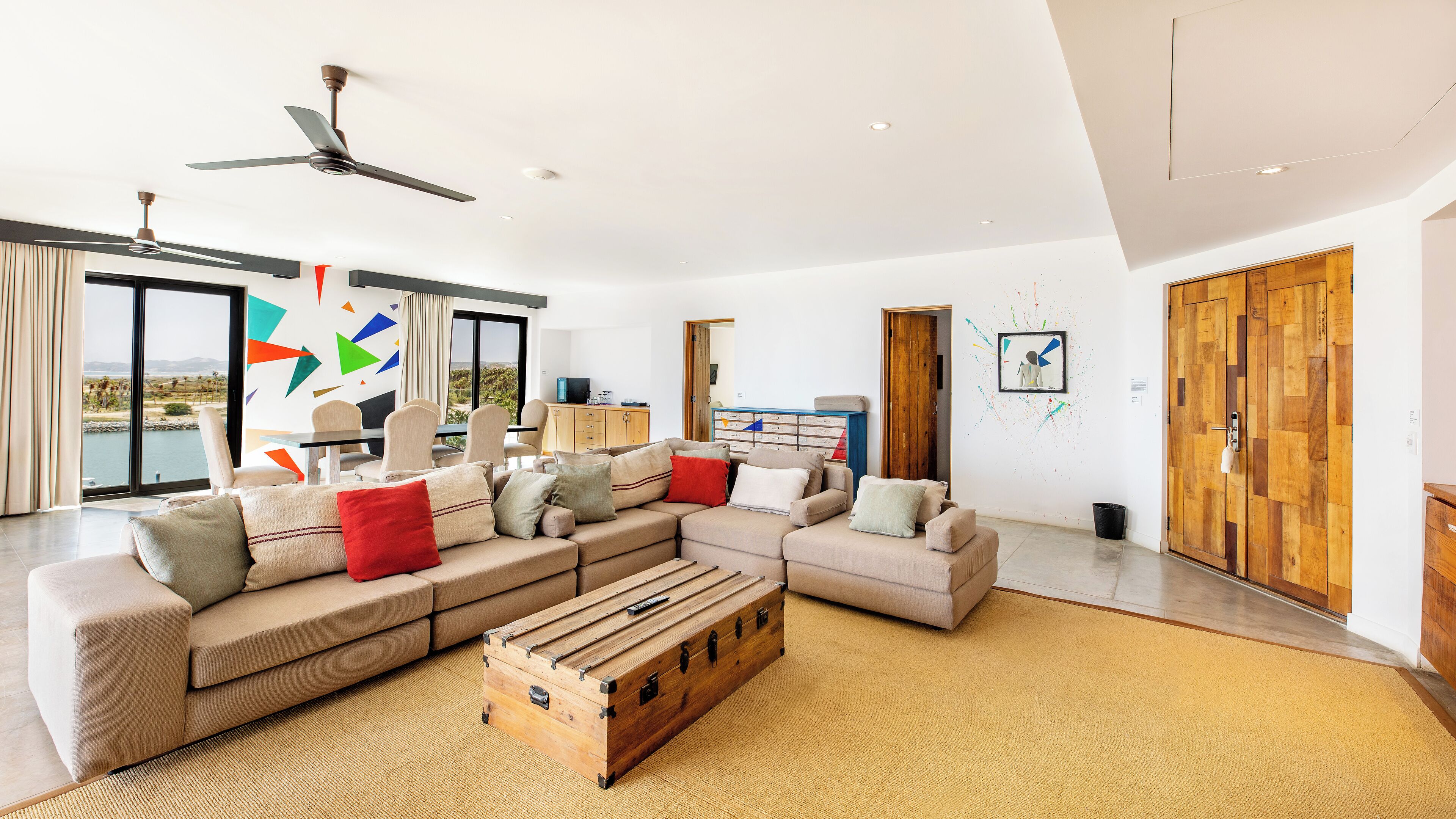 A spacious living room with a sectional sofa, a wooden chest, and a view of the outdoors.