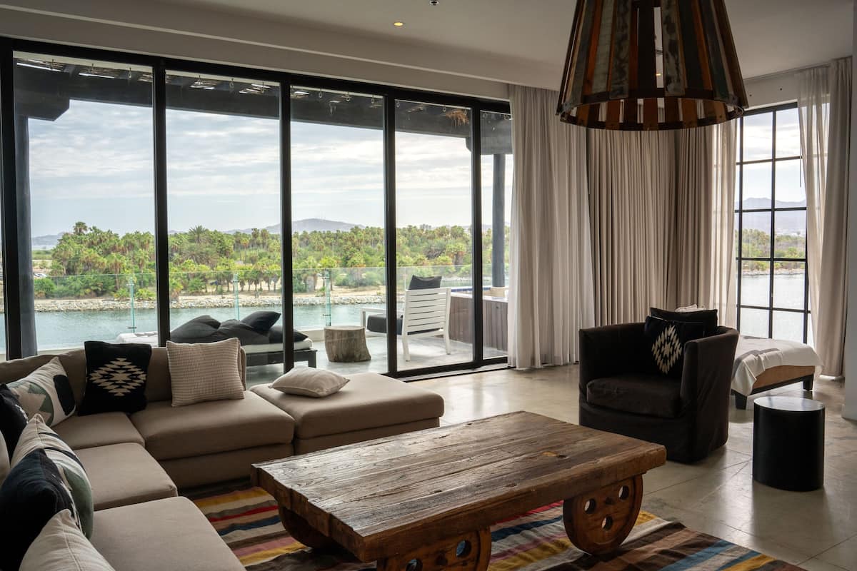 A spacious living room with a large sofa, a wooden coffee table, and a view of a pool and greenery.