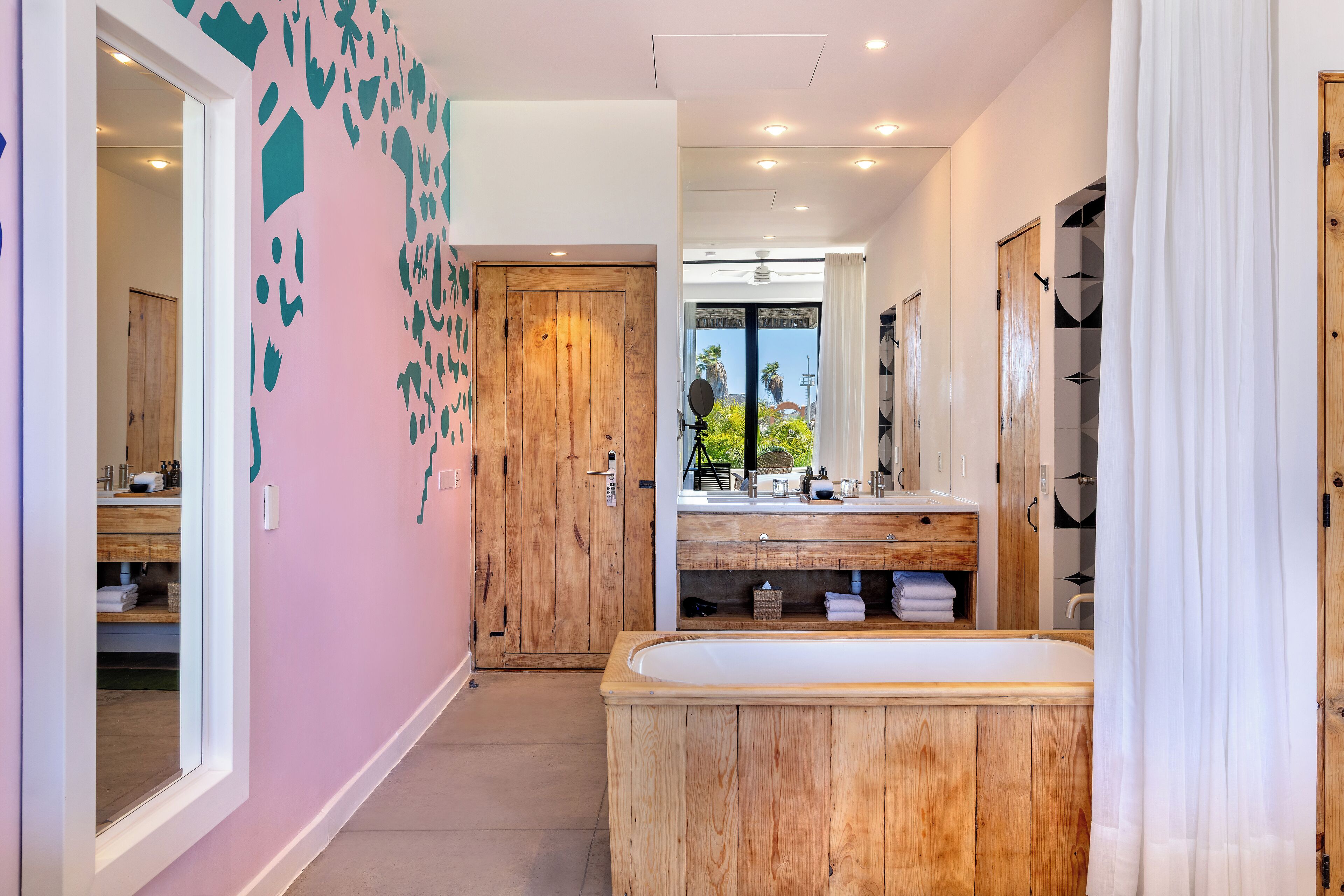 A modern bathroom with a wooden vanity, a large mirror, and a bathtub.