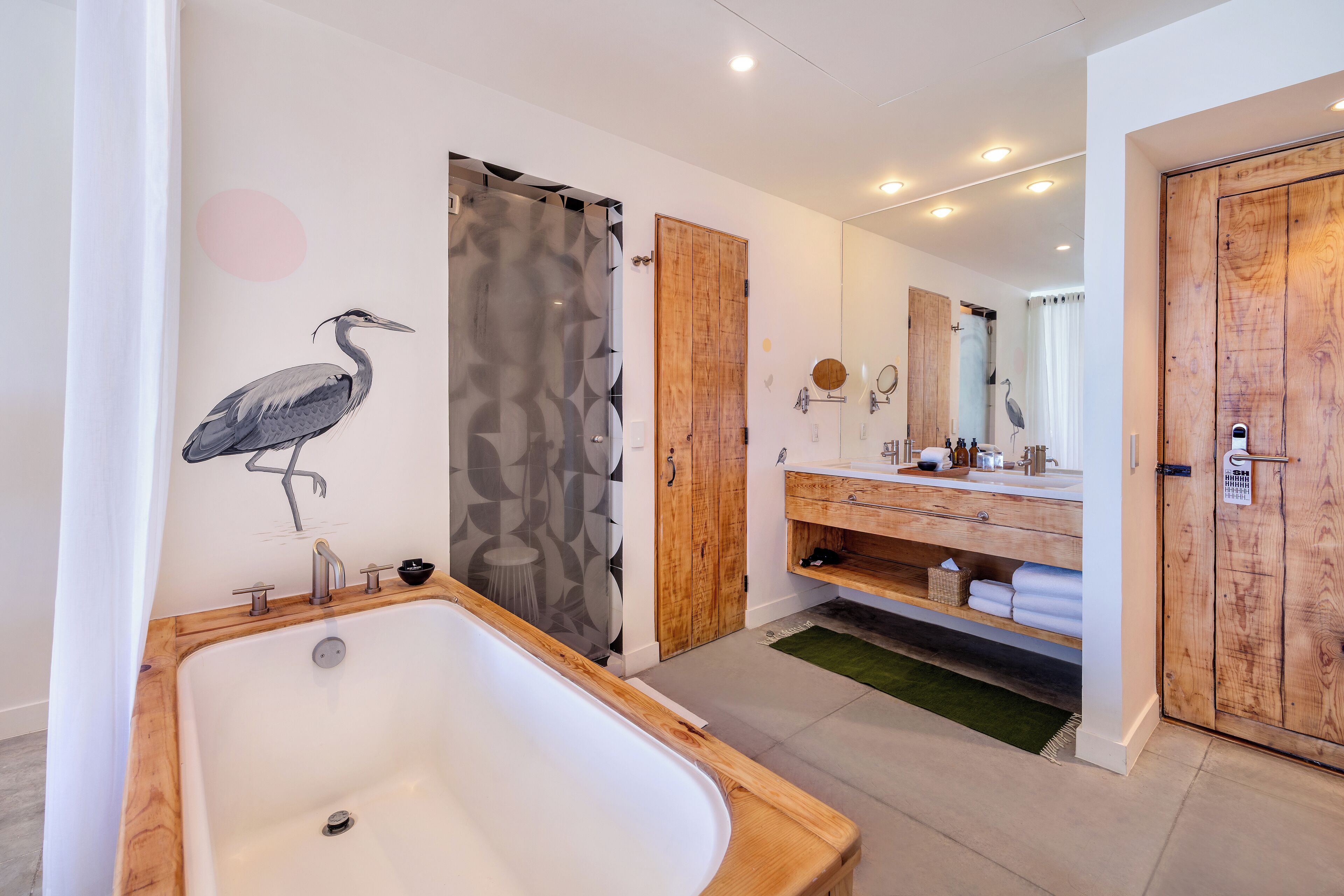 A modern bathroom with a freestanding bathtub, wooden vanity, and a large mirror.
