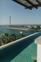 A view of a marina with boats, palm trees, and a clear sky.
