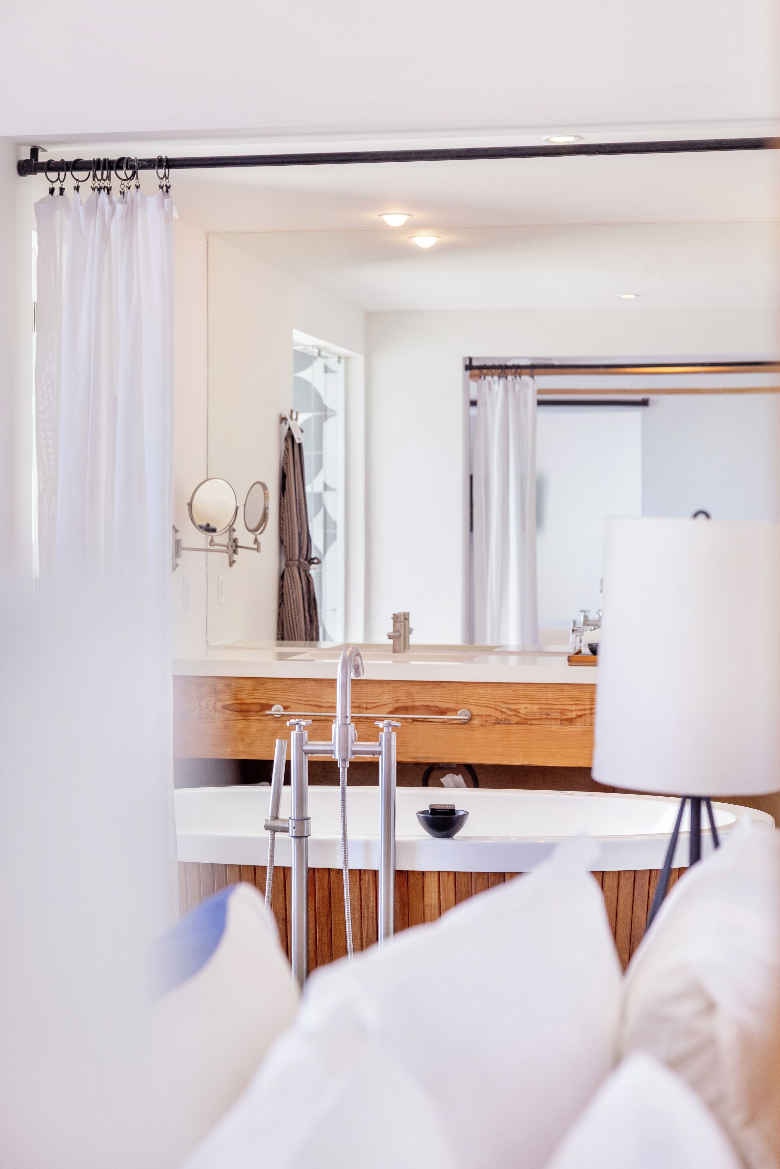 Un baño moderno con tocador de madera, un espejo grande y cortina de ducha.