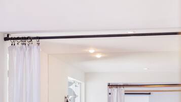A modern bathroom with a wooden vanity, a large mirror, and a shower curtain.