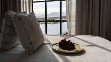 Una cama con vista a un lago y montañas a través de una ventana.