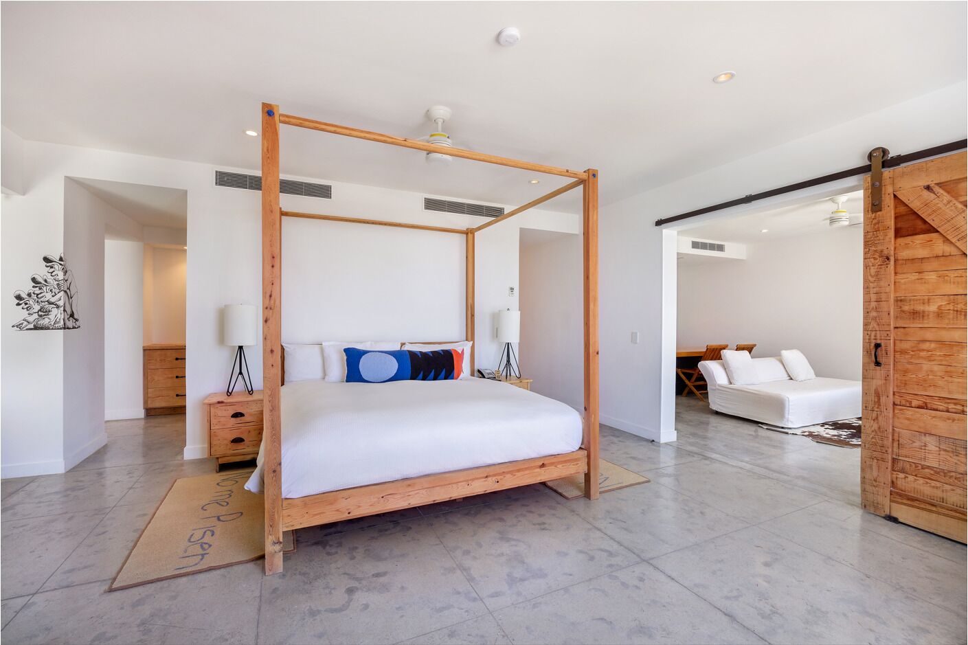 Un dormitorio moderno con una cama con dosel, un armario de madera y una zona de estar separada con un sofá.