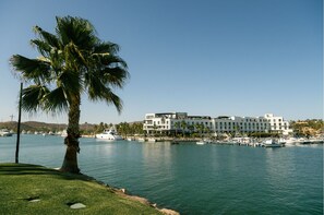 A waterfront hotel with a modern design, featuring multiple balconies and a marina with boats.