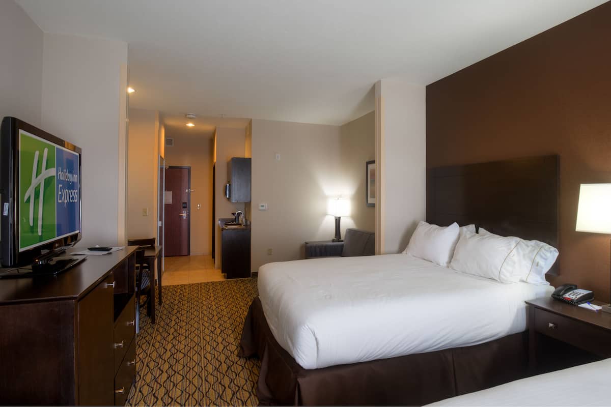 Ein Hotelzimmer mit Bett, Nachttisch, Lampe und Fernseher auf einem Schreibtisch.